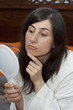 Young woman looks in the mirror