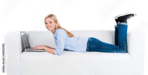 Photo: studentin liegt mit dem laptop auf dem sofa studentin liegt mit dem laptop auf dem sofa