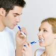 Photo: Cheerful young couple cleaning teeth together Cheerful young couple cleaning teeth together