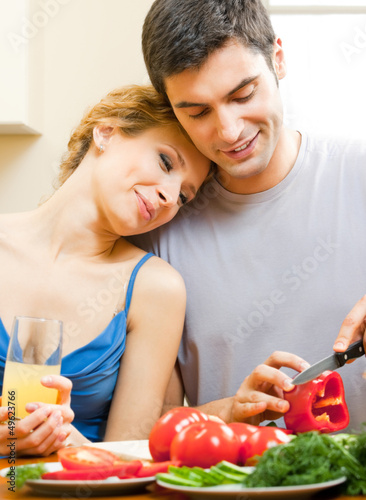 Photo: Cheerful young cooking couple at home Cheerful young cooking couple at home
