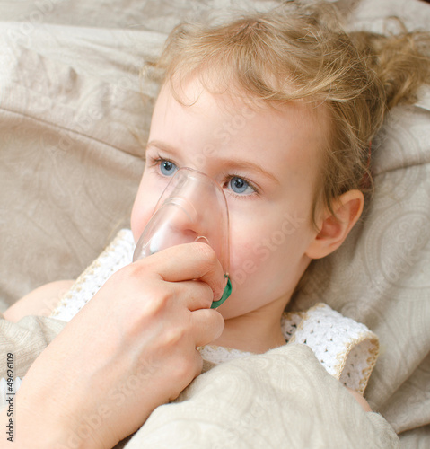 Photo: Girl lying in bed with inhalator mask on the face Girl lying in bed with inhalator mask on the face