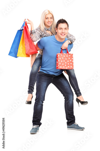 Photo: Happy young man giving a piggyback ride to his girlfriend with s Happy young man giving a piggyback ride to his girlfriend with s