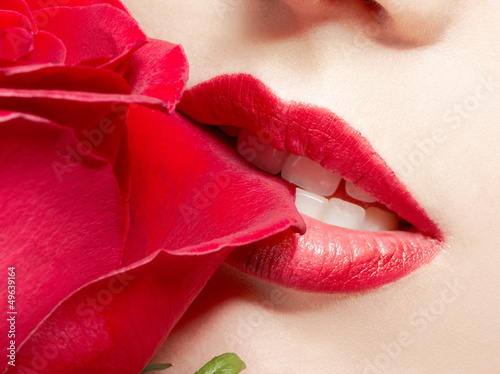 Photo: young woman biting rose young woman biting rose