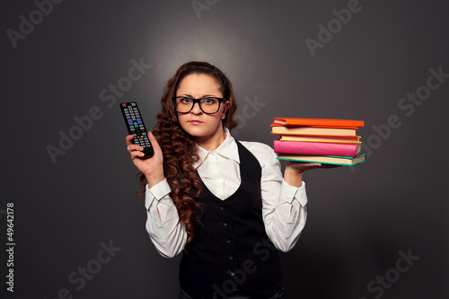 Photo: woman in glasses choosing between tv and books woman in glasses choosing between tv and books