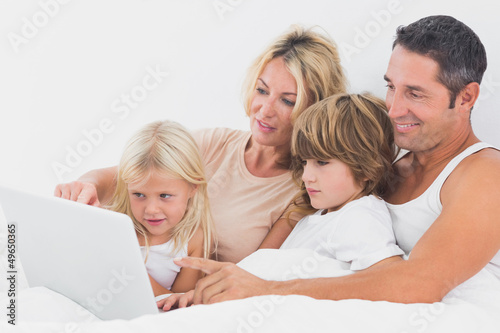 Photo: Family watching a laptop screen together Family watching a laptop screen together