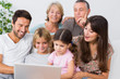 Photo: Smiling family watching something on laptop Smiling family watching something on laptop