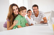 Photo: Happy family looking at the camera with a laptop Happy family looking at the camera with a laptop