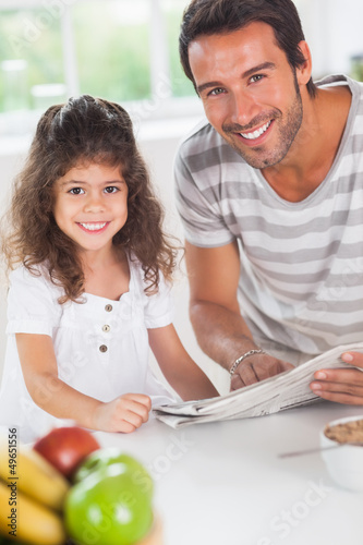 Photo: Dad and daughter reading a newspaper during breakfast Dad and daughter reading a newspaper during breakfast
