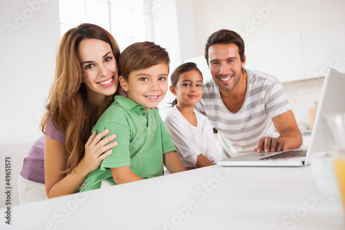 Photo: Happy family looking at the camera with a laptop Happy family looking at the camera with a laptop