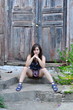 The girl sits on steps near an old door