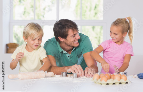 Photo: Father and his children cutting cookies out Father and his children cutting cookies out