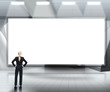 Businesswoman looking up at large blank screen under lights