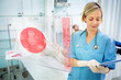 Photo: Nurse consulting tablet with screen displaying ECG in foreground Nurse consulting tablet with screen displaying ECG in foreground