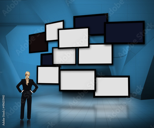 Photo: Group of blank screens on blue background with businesswoman loo Group of blank screens on blue background with businesswoman loo