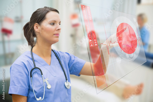 Photo: Nurse touching screen showing red ECG data Nurse touching screen showing red ECG data