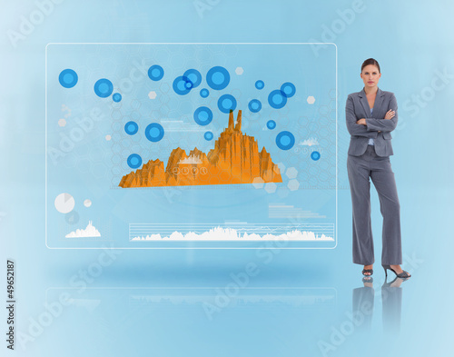 Photo: Serious businesswoman standing near to a futuristic screen Serious businesswoman standing near to a futuristic screen