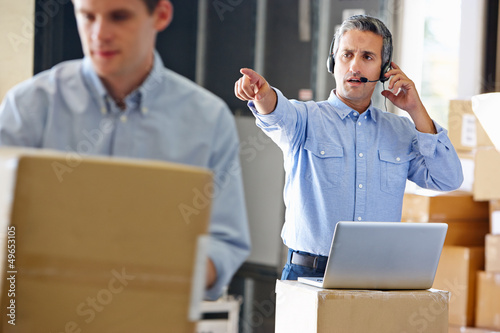Photo: Manager Using Headset In Distribution Warehouse Manager Using Headset In Distribution Warehouse