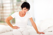 mature woman sitting on bed and having stomach ache