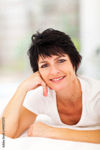 Photo: attractive middle aged woman lying on bed at home attractive middle aged woman lying on bed at home