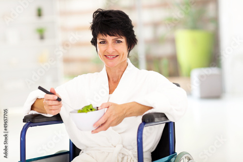 Photo: recovering middle aged woman eating salad on wheelchair recovering middle aged woman eating salad on wheelchair