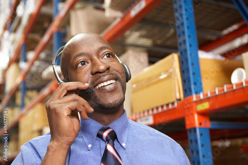 Photo: Businessman Using Headset In Distribution Warehouse Businessman Using Headset In Distribution Warehouse