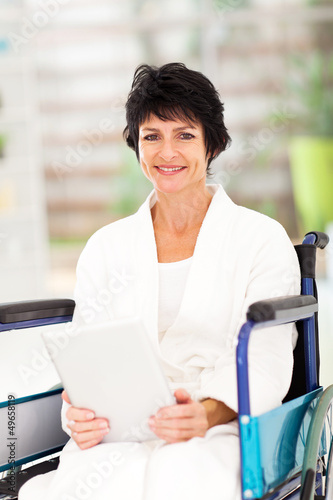 Photo: handicapped middle aged woman using tablet computer at home handicapped middle aged woman using tablet computer at home