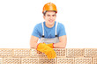 Male construction worker resting on a brick wall