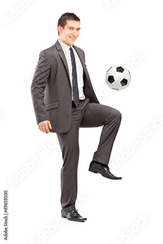Photo: Full length portrait of a young handsome businessman kicking a f Full length portrait of a young handsome businessman kicking a f