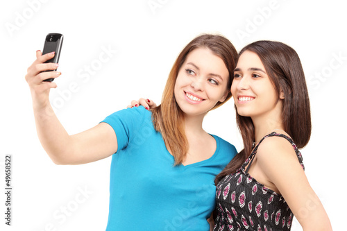 Photo: Two happy teenagers taking pictures of themselves with a cell ph Two happy teenagers taking pictures of themselves with a cell ph
