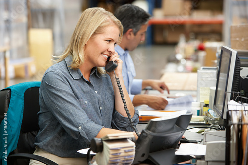 Photo: Businesswoman Working At Desk In Warehouse Businesswoman Working At Desk In Warehouse