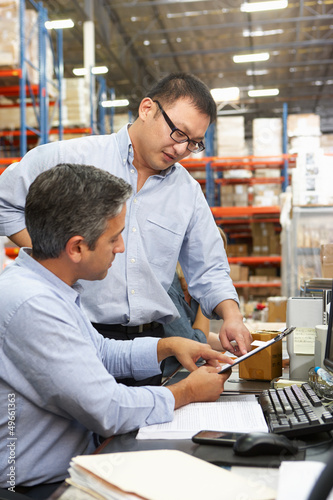 Photo: Business Colleagues Working At Desk In Warehouse Business Colleagues Working At Desk In Warehouse