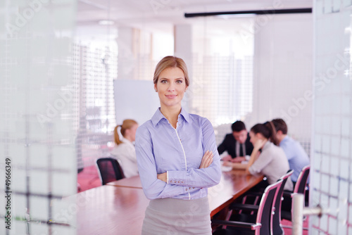 Photo: business woman with her staff in background at office business woman with her staff in background at office