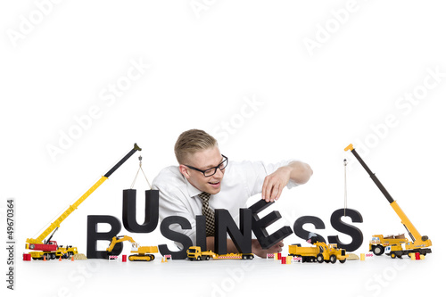 Photo: Business start up: Businessman building business-word. Business start up: Businessman building business-word.