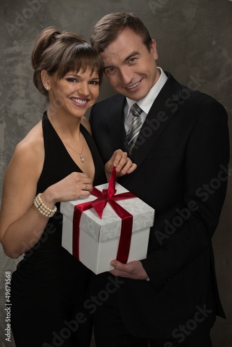 Photo: Young smiling man and woman with gift box Young smiling man and woman with gift box