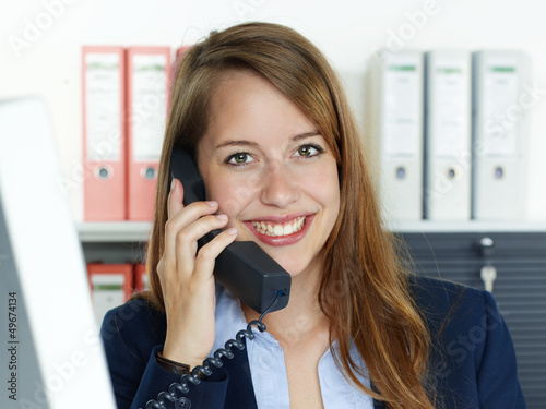 Photo: Female office assistant has a call at the office Female office assistant has a call at the office