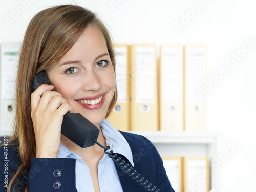 Photo: Female office assistant has a call at the office Female office assistant has a call at the office