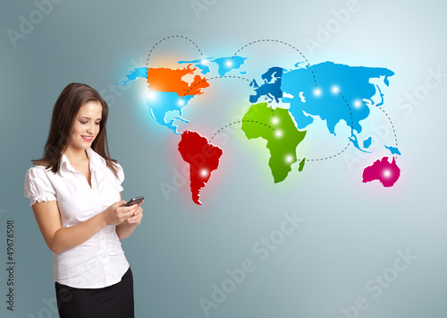 Photo: Young woman holding a phone and presenting colorful world map Young woman holding a phone and presenting colorful world map