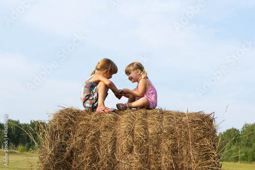 Photo: Two girls sit on haystack Two girls sit on haystack