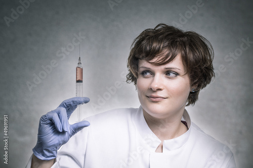 Photo: Wissenschaftlerin beäugt Spritze mit roter Flüssigkeit Wissenschaftlerin beäugt Spritze mit roter Flüssigkeit