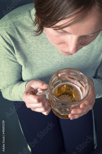 Photo: Young girl sitting on floor with light beer from the glass jug Young girl sitting on floor with light beer from the glass jug