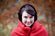 A woman wrapped up in a blanket wearing earmuffs