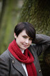 A woman leaning against a tree in autumn time