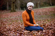 A woman sitting on the ground peeling a clementine