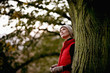 A woman standing next to a tree looking upwards
