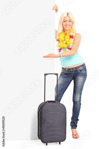 Photo: Full length portrait of a young female with suitcase pointing on Full length portrait of a young female with suitcase pointing on