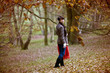 A woman walking in autumn time holding a blanket and flask