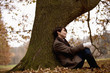 A woman sitting beneath a tree in autumn time