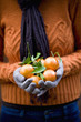 A woman holding a handful of clementines