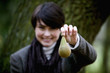 A woman holding a pear in front of her