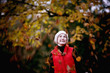 A woman standing amongst falling autumn leaves